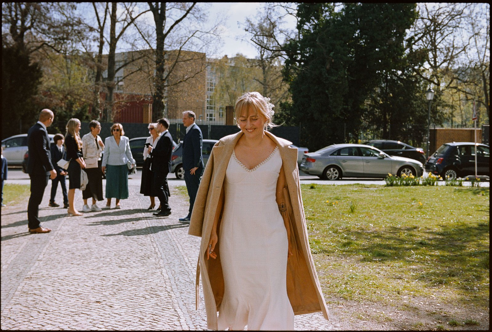 The bride walking outdoors, guests behind