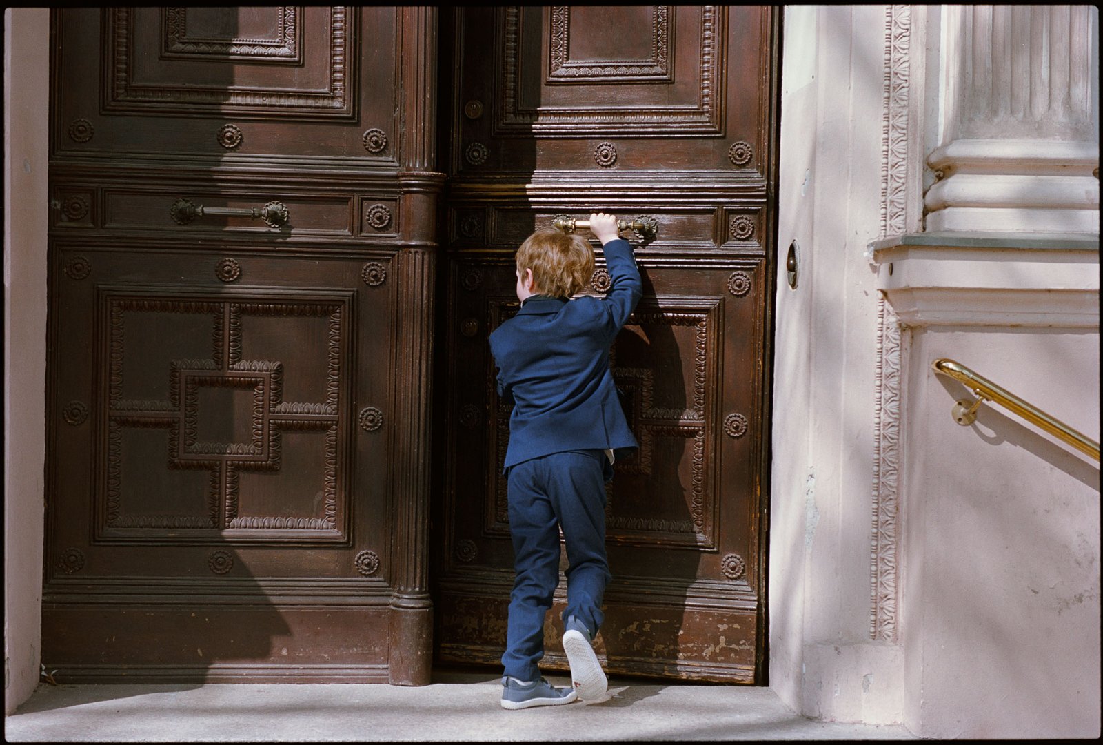 A child pushing open a large wooden door