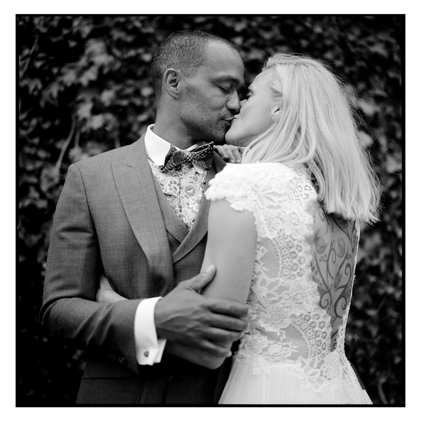 The couple in a close embrace among greenery, the groom's brow resting against the bride's, black and white, Linda & Thomas wedding in Berlin