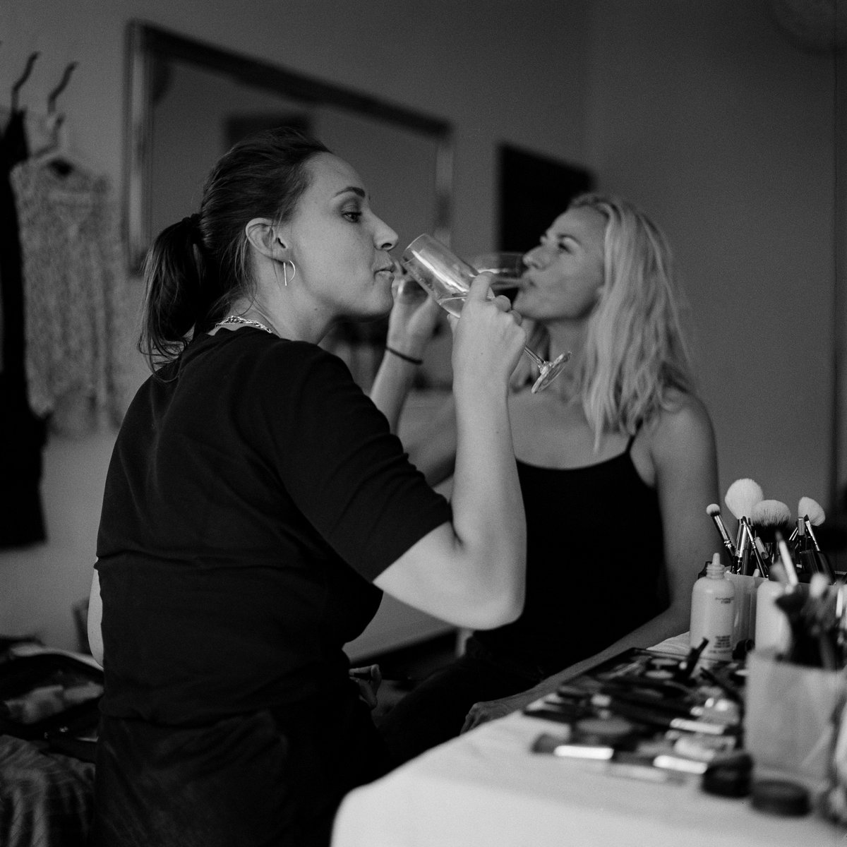 The bride sipping a drink during hair and make-up, black and white, Linda & Thomas wedding in Berlin