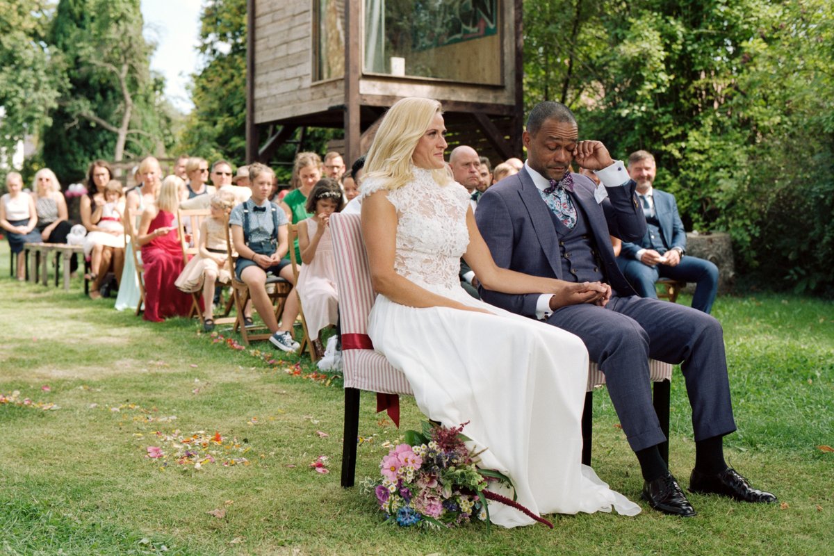 The couple seated together during the outdoor garden ceremony