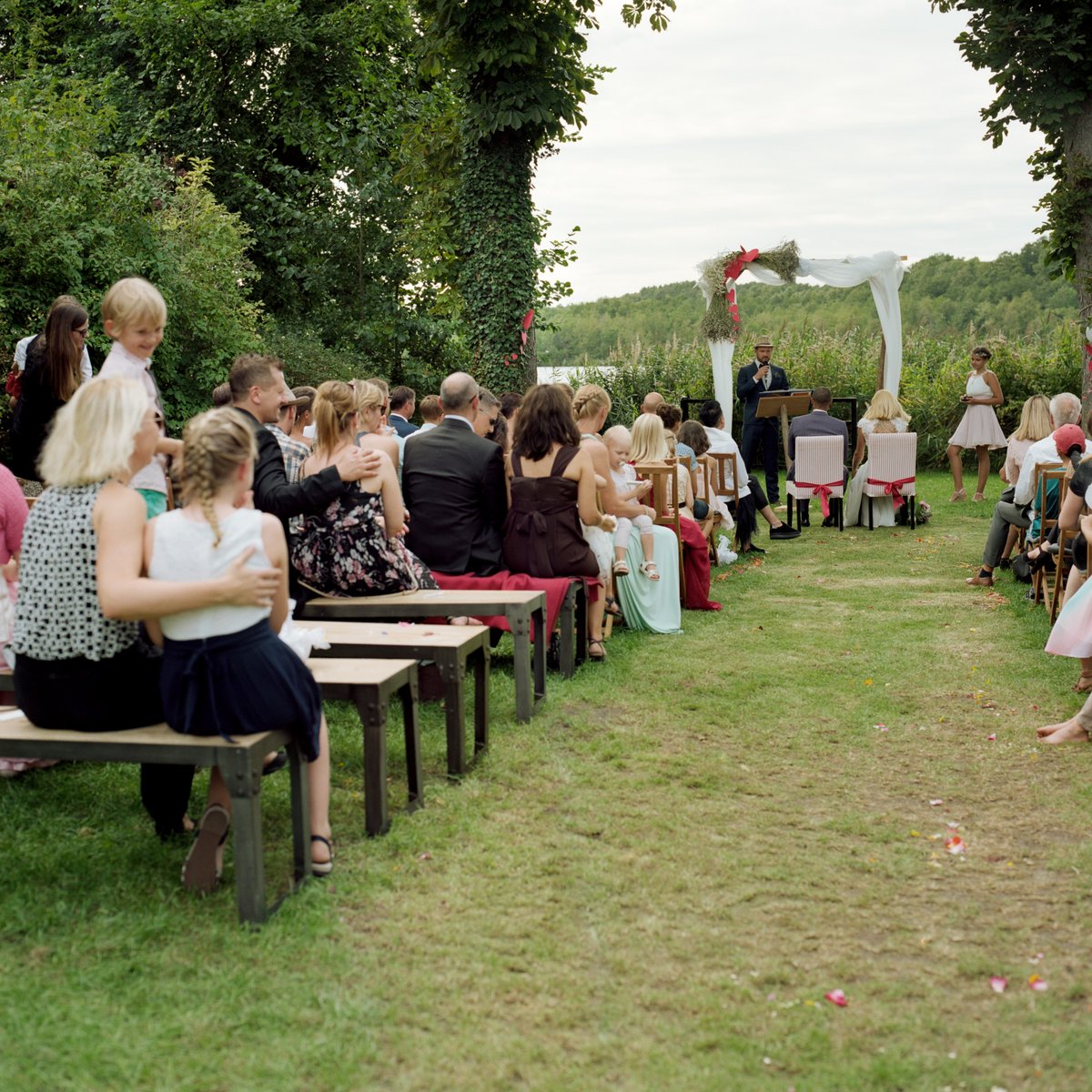 Guests seated on benches for the lakeside garden ceremony