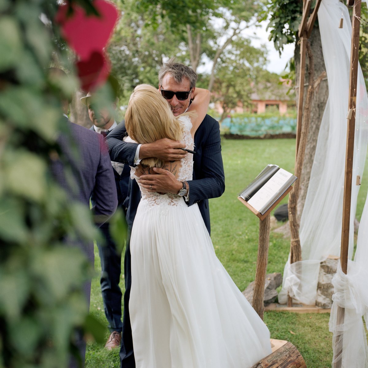 The bride embracing a guest beside the flower-covered arch
