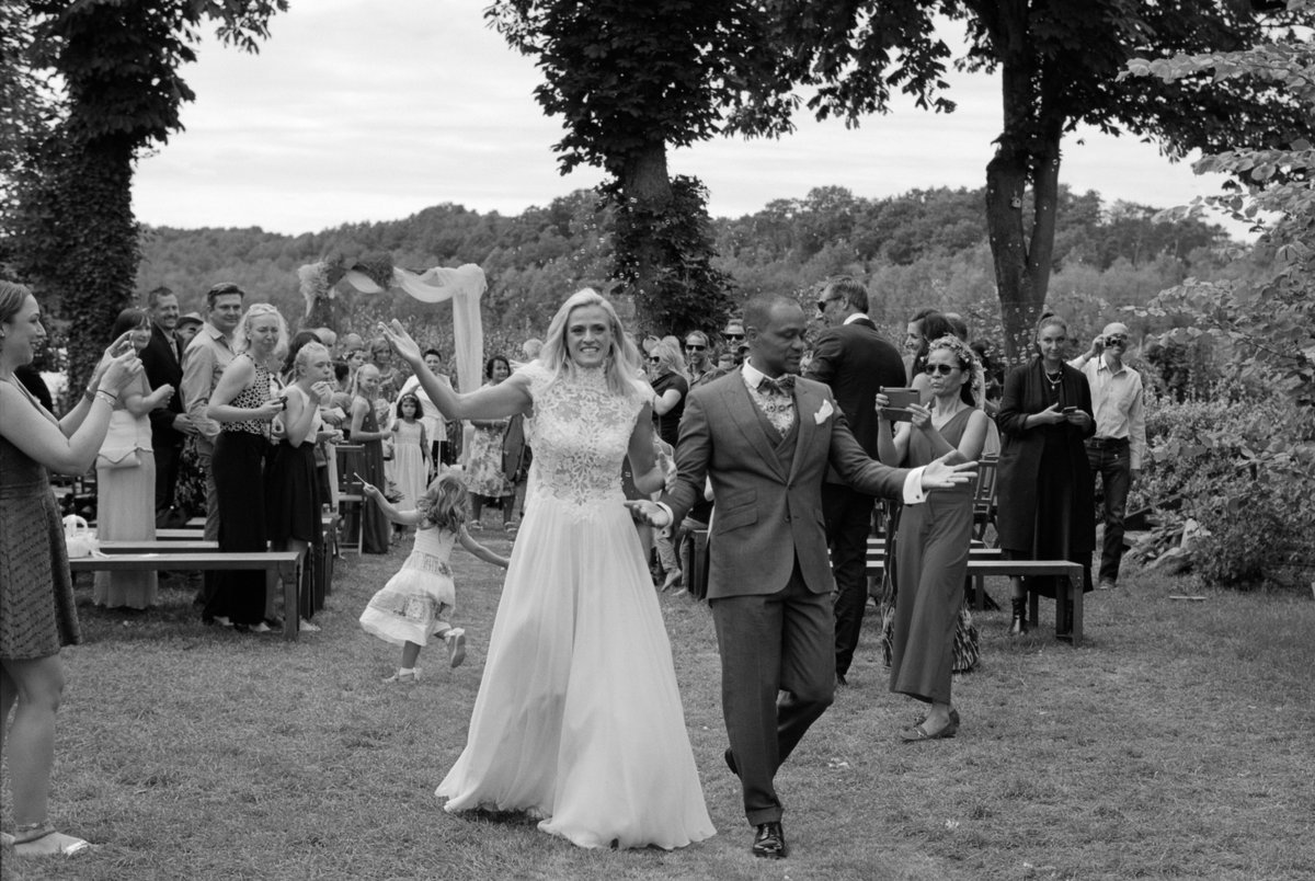The couple walking through the garden with their guests, black and white