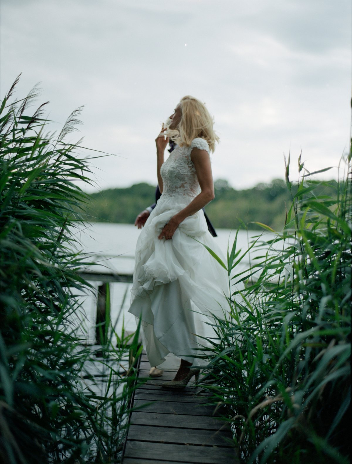 The bride at the water's edge among the reeds at dusk