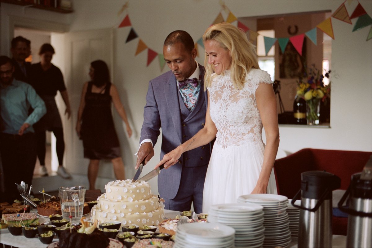 The couple cutting their cake beneath the bunting