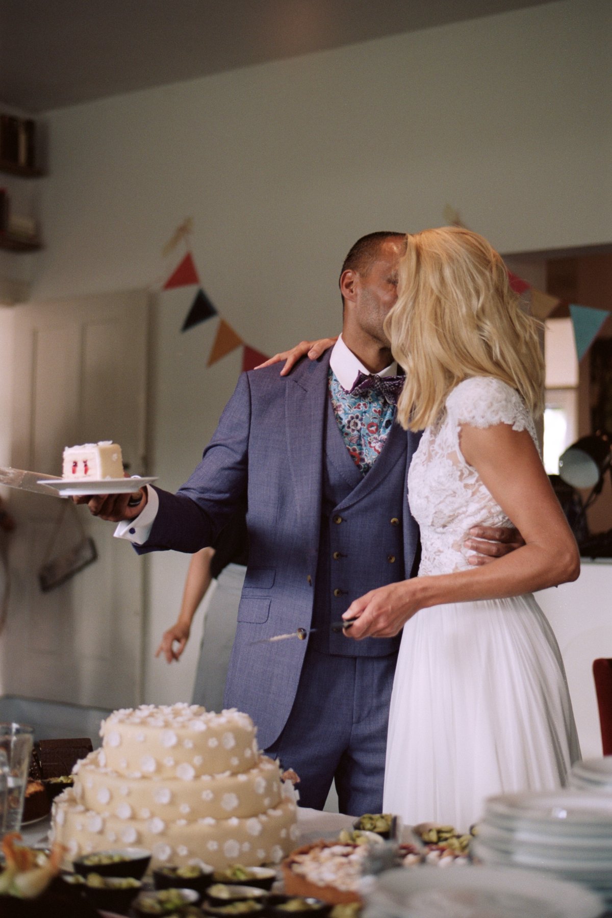 The couple beside their cake under paper bunting indoors