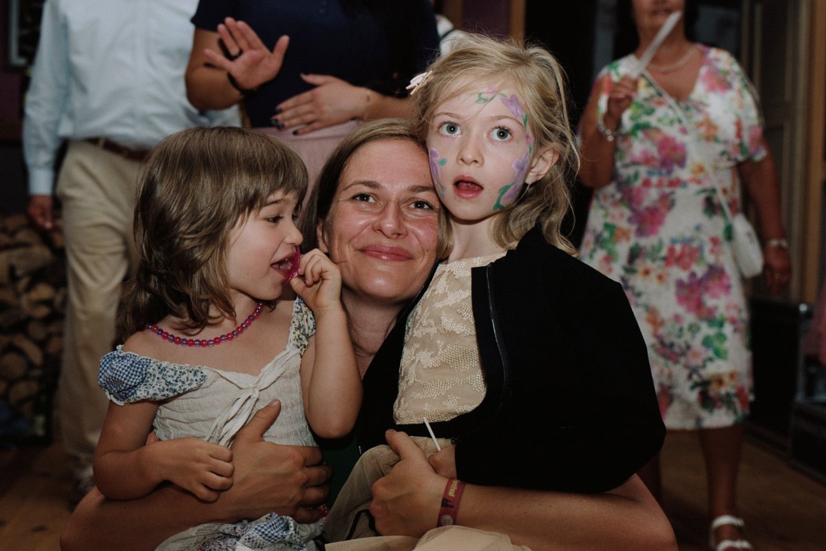 A guest holding two children with painted faces
