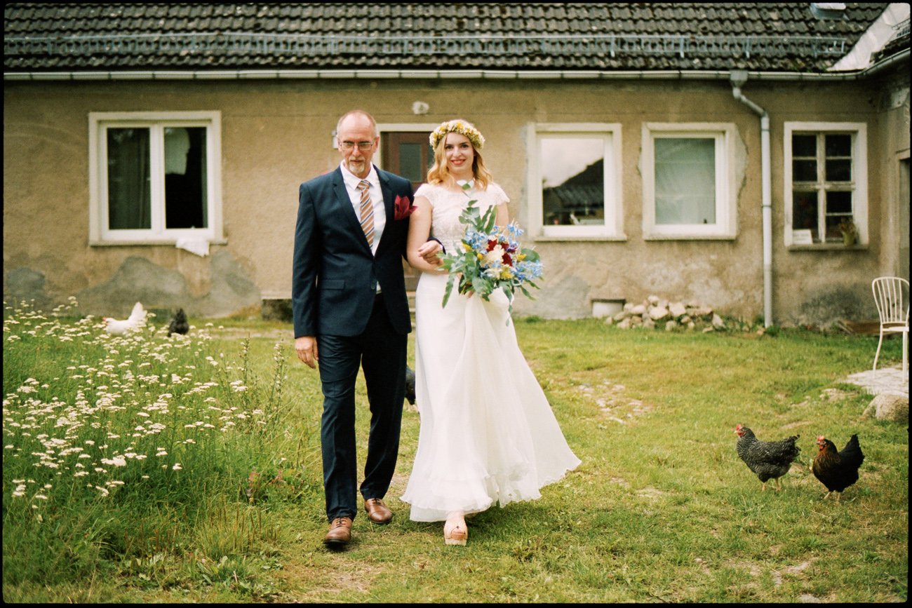 Die Braut geht mit ihrem Vater über den Garten
