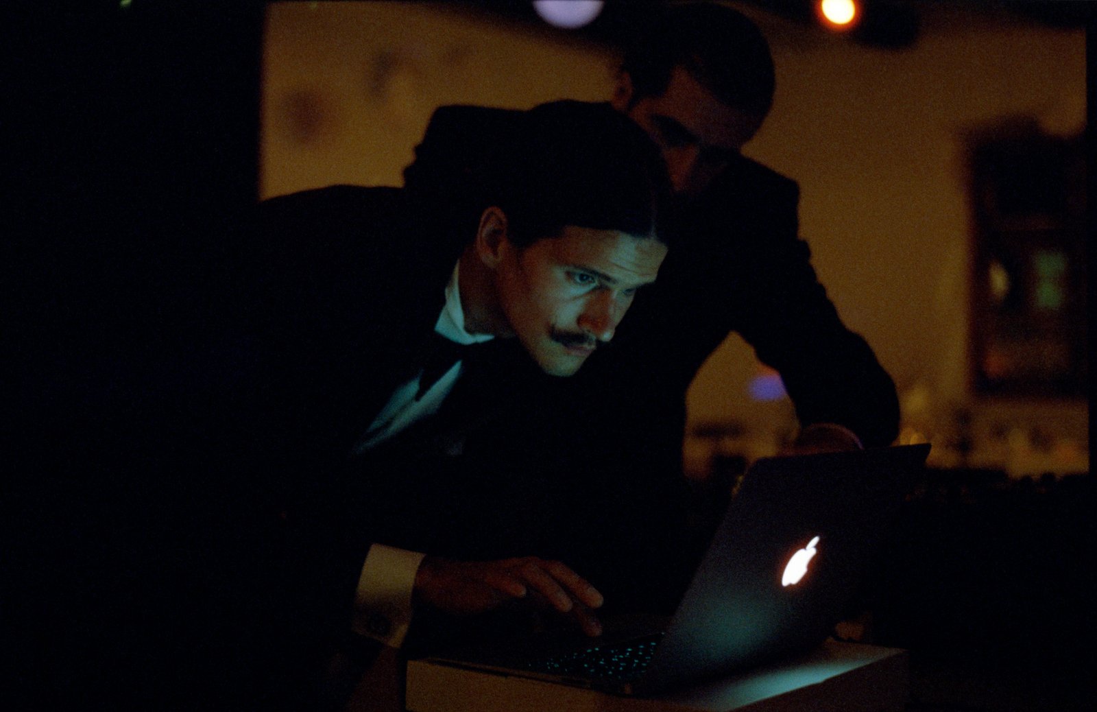 Ein Gast am Laptop während der Party, vom Bildschirm beleuchtet