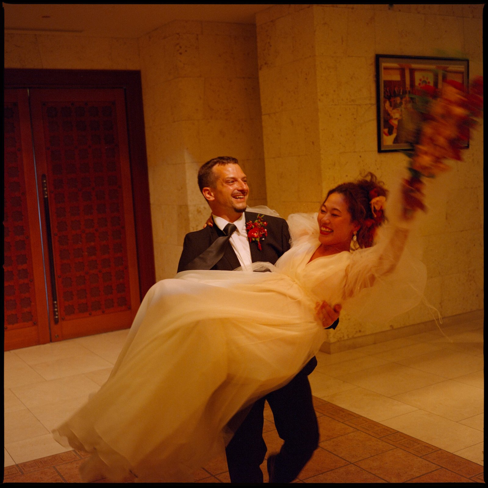 The groom carrying the bride, arms thrown up