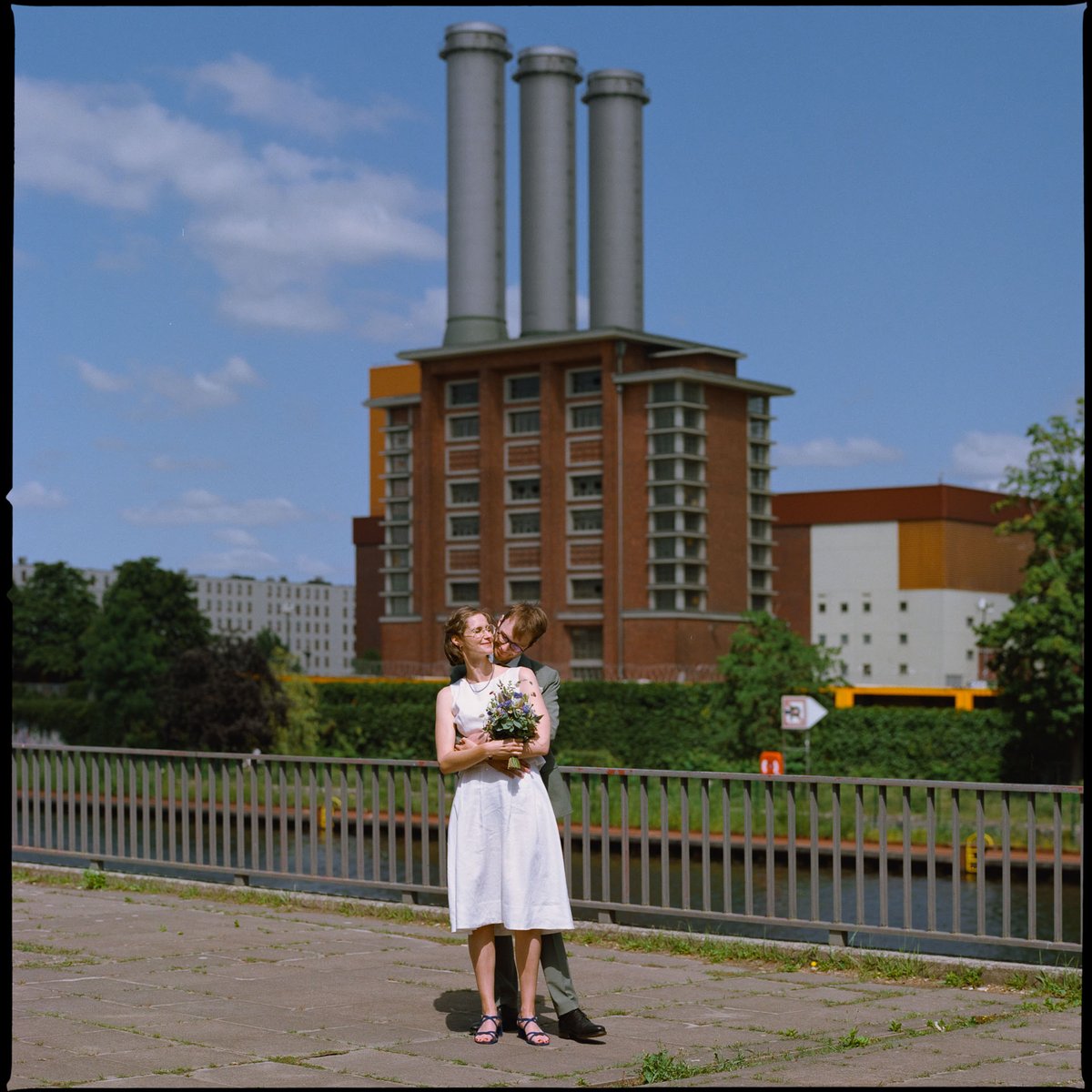 Newlyweds standing on a bridge in front of a Berlin power station, 35mm film photograph