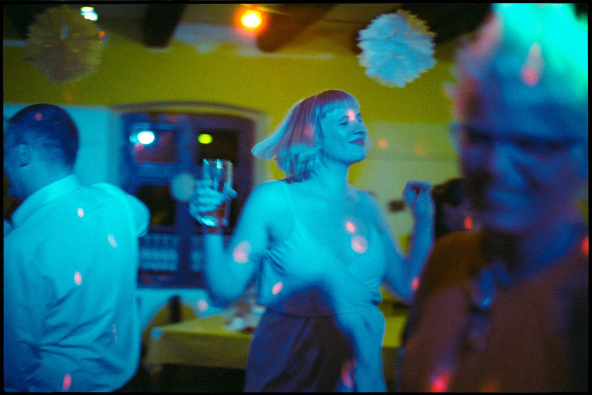 Gast tanzt spät am Abend mit einem Glas in der Hand im farbigen Licht