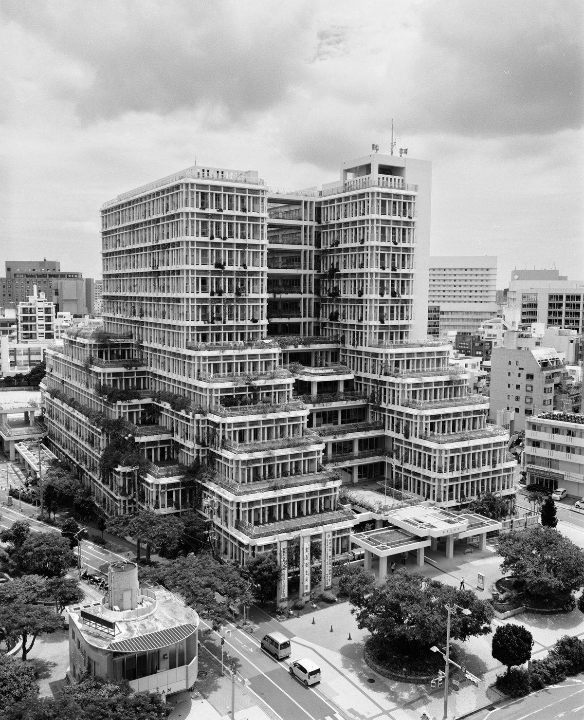 Gestuftes Betonhochhaus, aus jeder Terrasse quellen Pflanzen