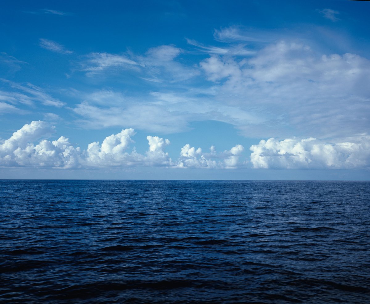 Offenes Meer unter einer Reihe von Quellwolken am Horizont